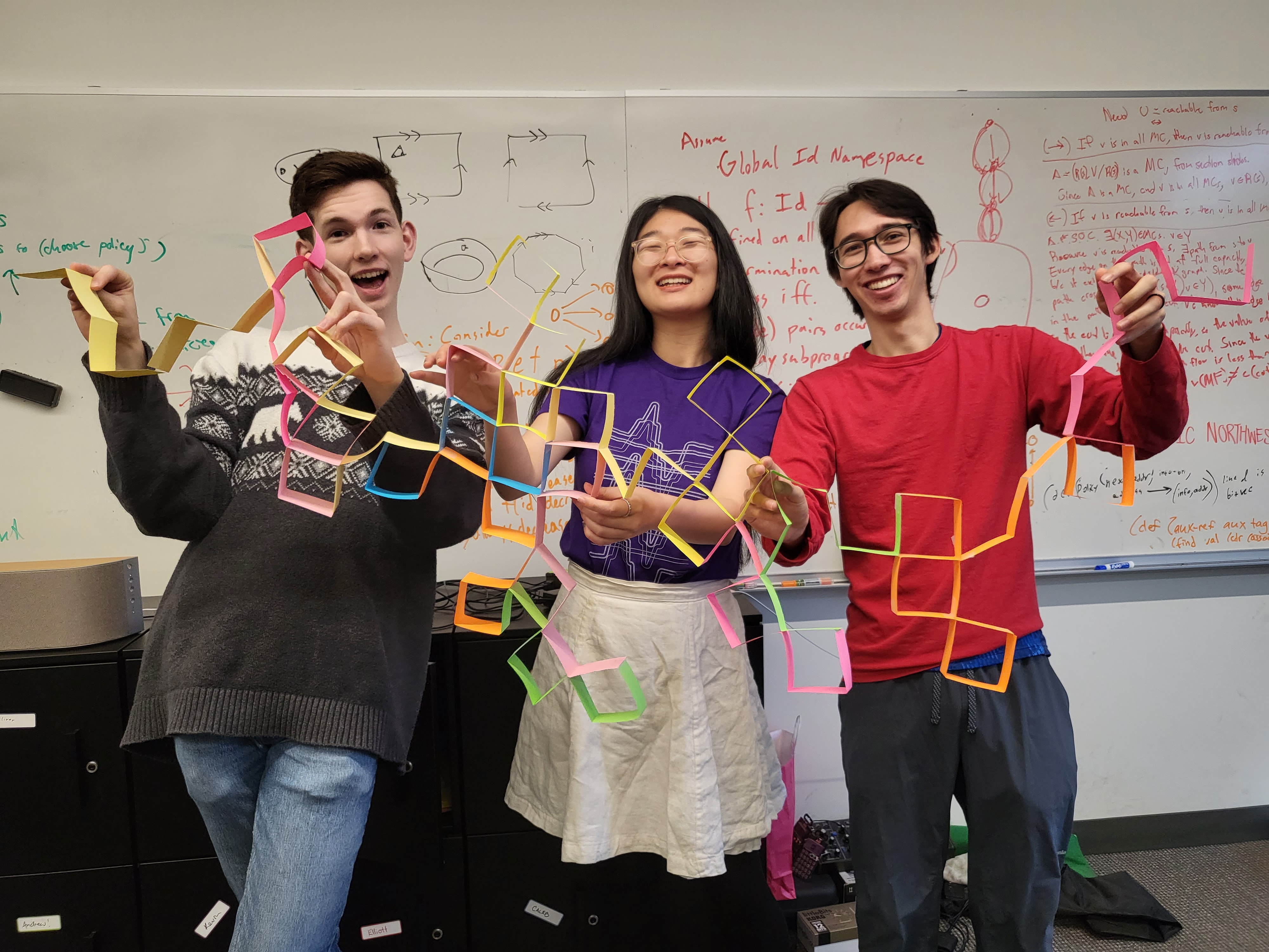 A picture of 3 PLSE students holding a paper dragon curve up